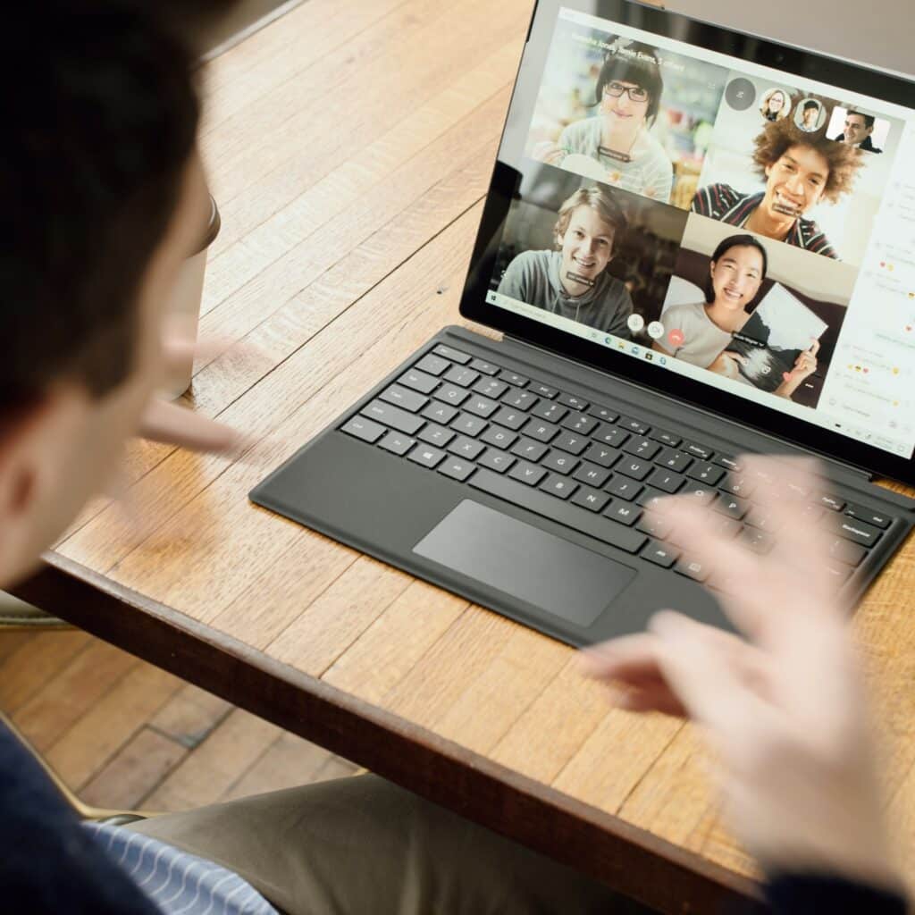 Man presents to video conference attendees on a laptop screen.