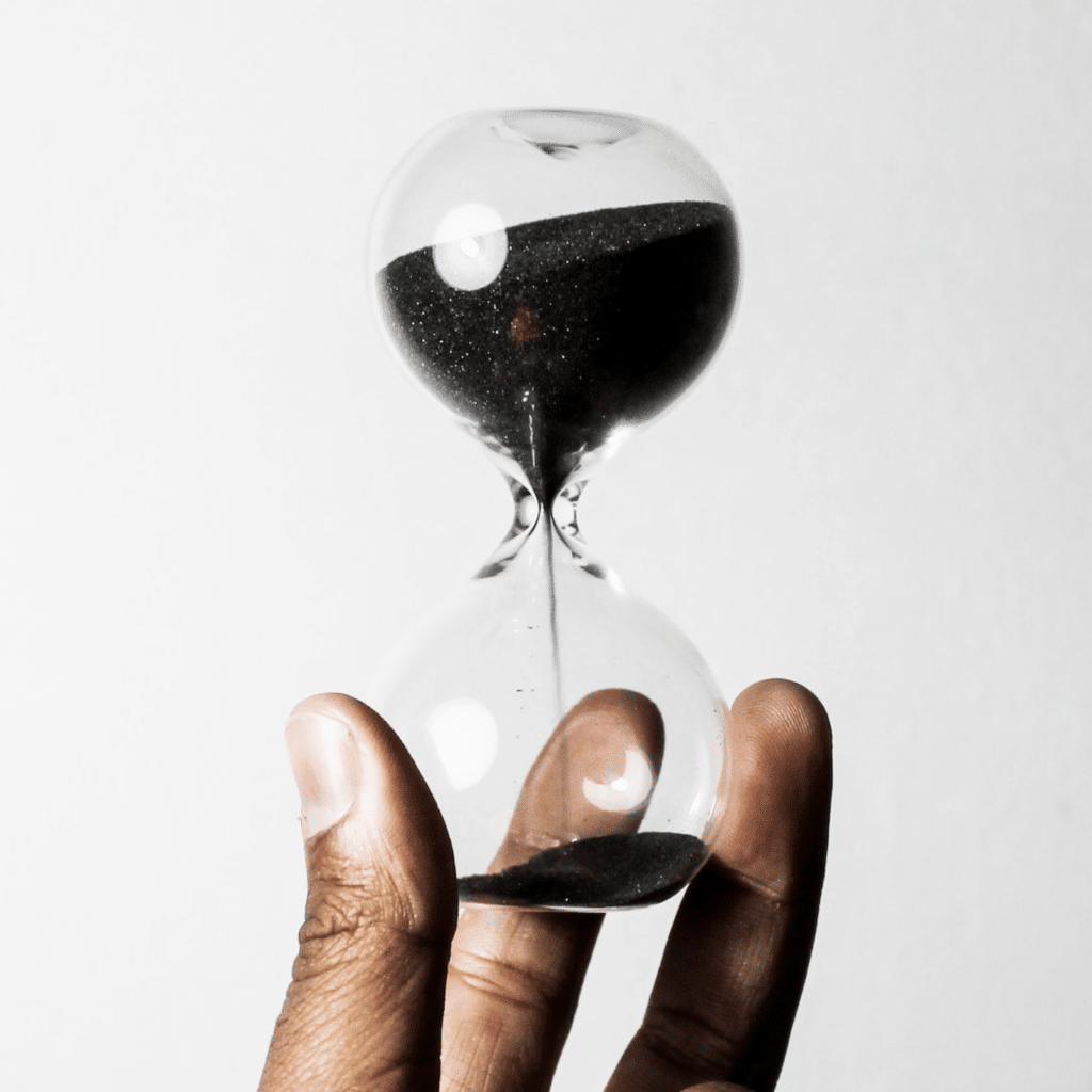 Close up photo of a man holding an hourglass to indicate urgency